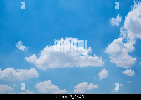Cumulus clouds against bright blue sky Stock Photo