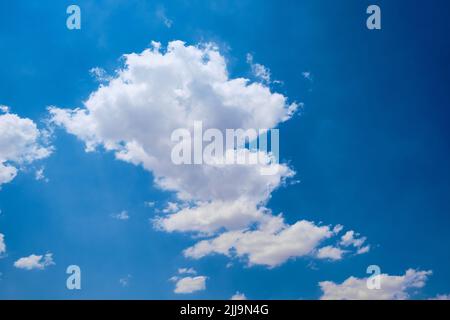 Cumulus clouds against bright blue sky Stock Photo