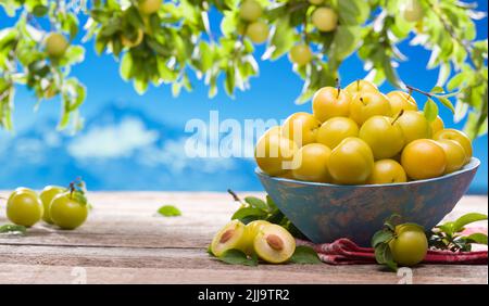 Yellow fresh cherry plum on the garden table. A bowl of yellow plums Stock Photo