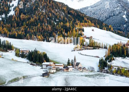 Famous Santa Magdalena mountain village with Church Chiesa di Santa Maddalena in the autumn Dolomites. Snowy Gruppo delle Odle mountain range in the background. Val di Funes, South Tyrol, Italy