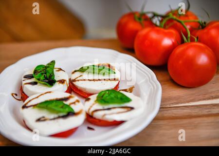tomatoes on the vine - Solanum lycopersicum - red tomato basil mozzarella salad - mozarella - vegetarian lifestyle & cooking food - ripe balsamic Stock Photo