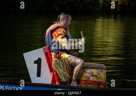 Man in Hawaiian shirt and grass skirt banging the drum in a Dragon Boat race Stock Photo