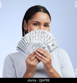 Show me the money. a young woman holding banknotes over her face. Stock Photo