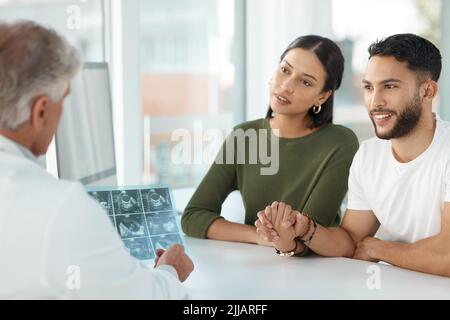 Your uterus is healthy enough to carry a baby. a young couple sitting with their obstetrician and holding hands during a consultation in the clinic. Stock Photo