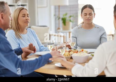 Be grateful, always. a beautiful family blessing the food with a prayer at the table together at home. Stock Photo