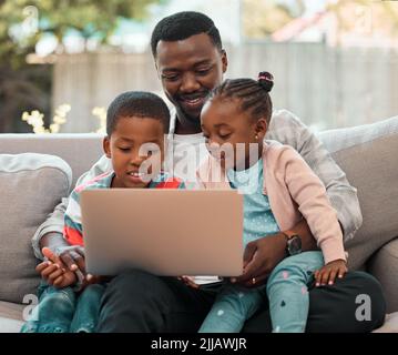 Spending time with family makes it all worth it. a young father using a laptop with his children at home. Stock Photo