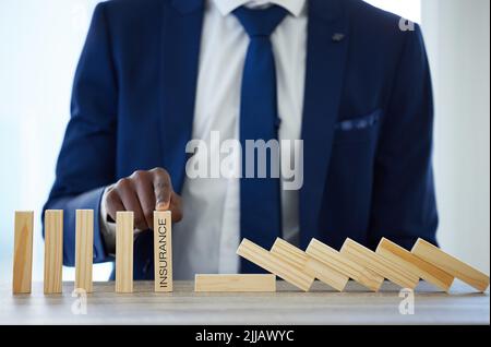 It can happen faster than you think. an unrecognisable businessman working with falling wooden blocks that have the word insurance on them. Stock Photo