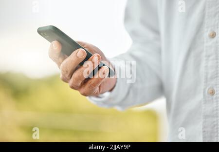 Text as you go. an unrecognizable man using his cellphone while standing outside. Stock Photo
