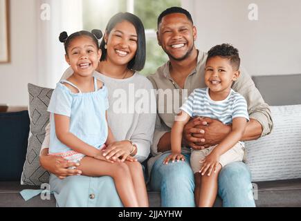 Colour in my life, give me joy. a young family happily bonding together on the sofa at home. Stock Photo