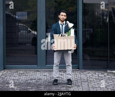 There is no failure except in no longer trying. a young businessman looking depressed after being retrenched from work. Stock Photo