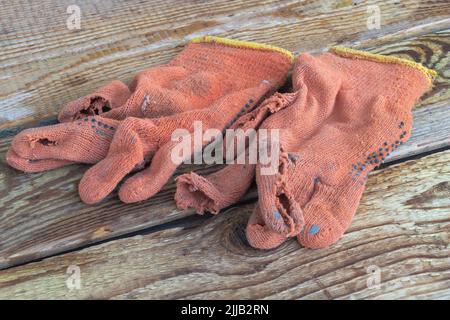 Some used and torn construction gloves on a wooden background Stock Photo