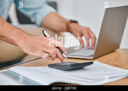 I should probably calculate this again. an unrecognisable man sitting alone on his sofa and using his laptop while calculating his finances. Stock Photo