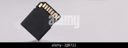 High quality black sd memory card with small gold disc on gray background Stock Photo