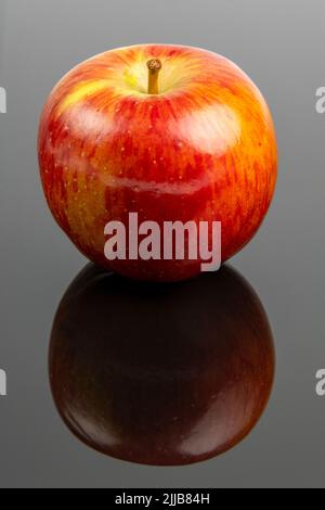 Braeburn apple on a dark reflective surface Stock Photo
