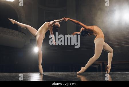 Dancing is the poetry of the foot. a group of ballet dancers practicing a routine on stage. Stock Photo