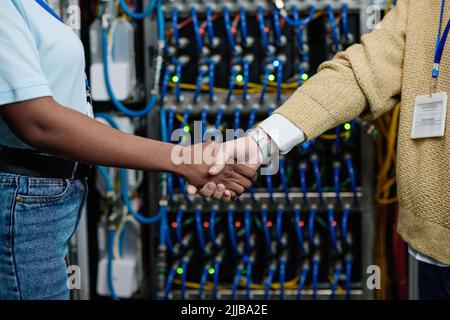 Close-up of female engineers shaking hands to each other during their teamwork in data center Stock Photo