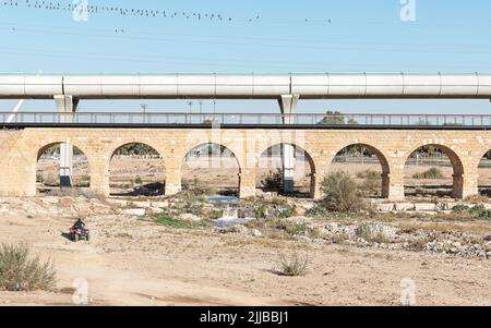 reconstructed limestone Ottoman era train bridge in front of a modern train bridge over the Beer Sheva River in Israel with a clear blue sky and an AT Stock Photo