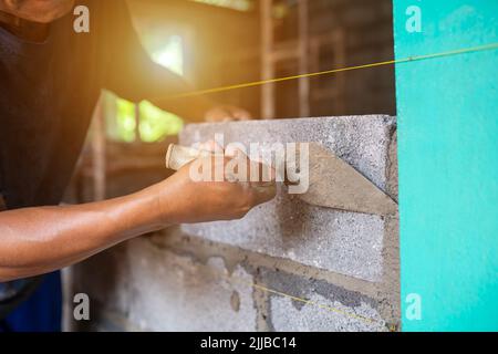Close-up shot of a bricklayer building a house or walls with mortar and bricks Stock Photo