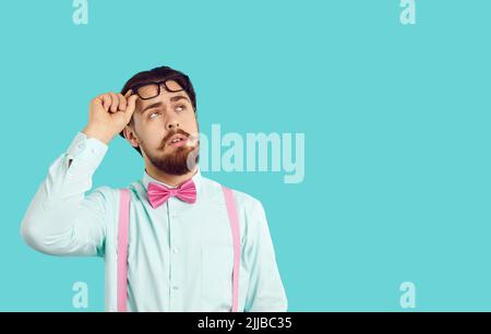 Bearded Caucasian man looks up, raising glasses from eyes dressed in white shirt Stock Photo