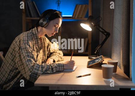 asian girl student doing homework with digital tablet at home late at night. use of gadgets for study. Education and distance learning for teenagers Stock Photo