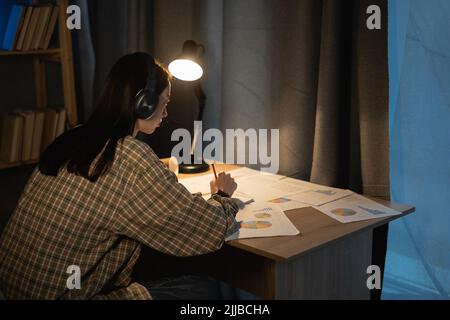Young asian girl working think idea for project and paper having problem at night at home, female student studing using notebook with frustrated and Stock Photo