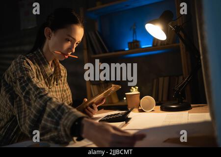 Handsome asian young girl using smartphone while studying in the evening at home. education, technology, overwork and people Stock Photo