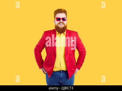 Funny bearded man in red glasses smiling looking at camera stands in colorful clothes for party Stock Photo