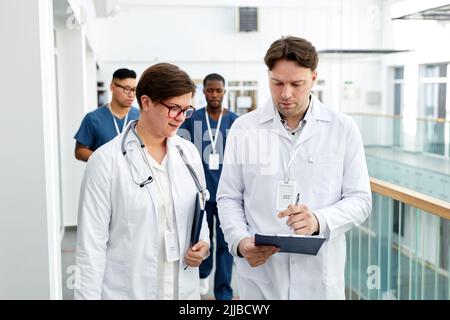 Waist up portrait of group of doctors holding clipboards while walking in hall of modern clinic Stock Photo