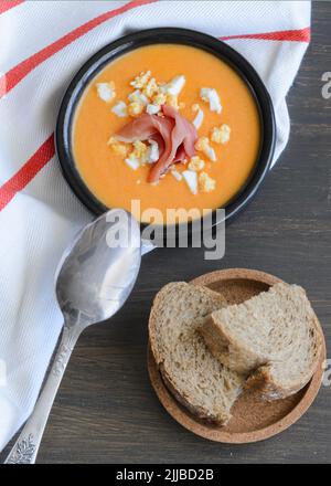 Close up of Salmorejo, creamy cold tomato soup, served with serrano ham and hard-boiled eggs. Traditional Spanish cuisine background. Stock Photo