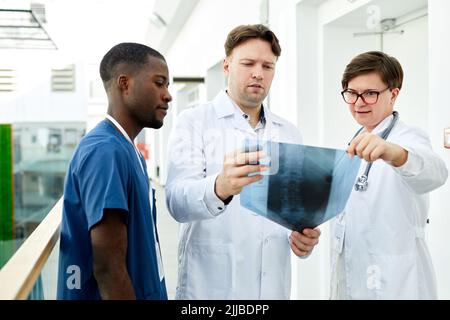 Waist up portrait of diverse group of doctors looking at x ray image in modern clinic, copy space Stock Photo