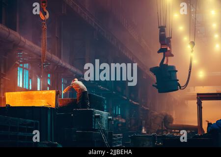 Metallurgy plant interior. Foundry worker on big mold for iron cast. Heavy industry. Steel factory. Stock Photo