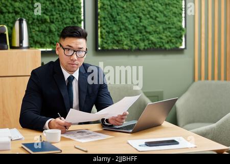 Portrait of handsome Asian businessman working with documents in conference room green eco design, copy space Stock Photo
