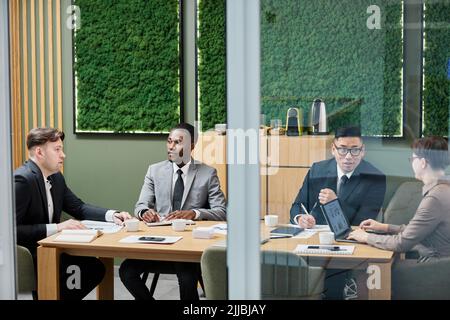 Diverse group of business people in formalwear meeting in conference room with green eco design Stock Photo