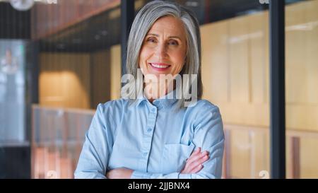 Portrait of smiling confident 60-s gray-haired mature woman. Stock Photo