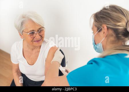A senior woman smiling and looking happy after getting vaccinated by a healthcare nurse. High quality photo Stock Photo