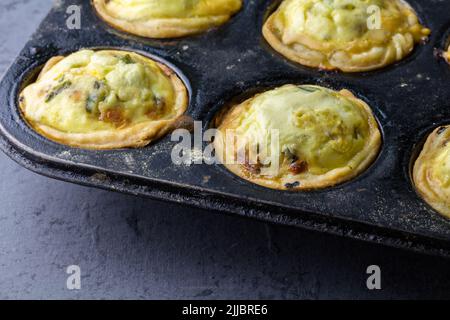 Mini quiche tarts in baking tray - small savoury pies Stock Photo