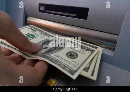 Close-up of a woman's hand withdrawing money from an ATM. Selective focus Stock Photo