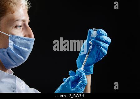 The doctor prepares to give the injection. A female nurse fills the syringe with medicine. Stock Photo