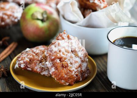 Glazed apple fritters and hot coffee with fresh apples, cinnamon bark and anise. Selective focus with blurred background. Stock Photo