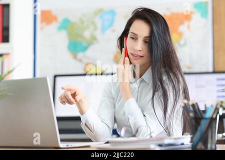 Business consultant positively talking on mobile phone working on laptop in office Stock Photo