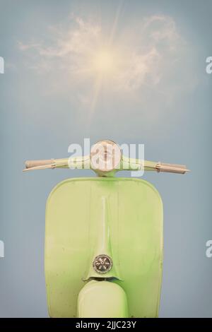 Retro styled image of a vintage green scooter in front of a blue sky with sunshine Stock Photo