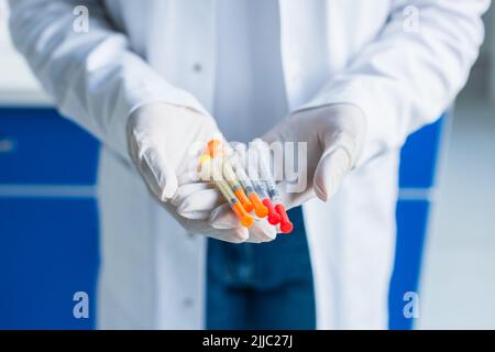 Cropped view of scientist in latex gloves holding syringes in lab Stock Photo