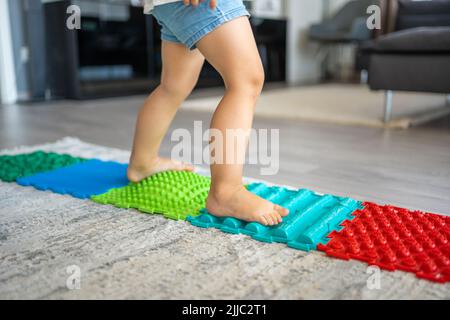 Toddler on baby foot massage mat. Exercises for legs on orthopedic