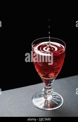 Luxurious cocktail in a crystal goblet with waves of drops on a dark stone background Stock Photo