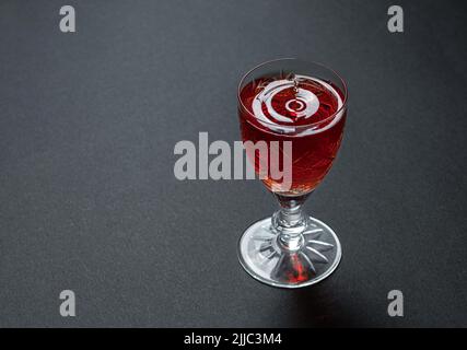 Luxurious cocktail in a crystal goblet with waves of drops on a dark stone background Stock Photo