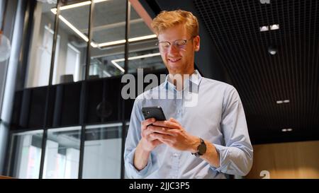 Middle aged businessman use smartphone computer apps for work in office. Stock Photo