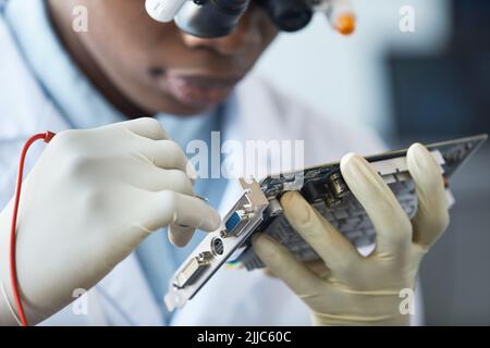 Close up of female engineer inspecting hardware part in laboratory Stock Photo