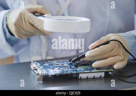 Closeup of unrecognizable female engineer inspecting hardware with magnifying glass, copy space Stock Photo