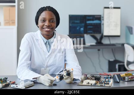 Portrait of smiling black woman as female engineer looking at camera in laboratory, copy space Stock Photo