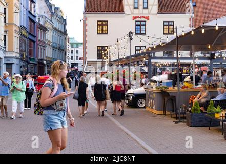 Riga street scene - tourists and crowd of local people mixing on a busy street in the evening as the bars opening, Riga Old Town, Riga Latvia Europe Stock Photo